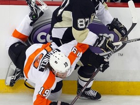Flyers Scott Hartnell (left) falls while checking Pens captain Sidney Crosby during Game 1 of their NHL playoff series in Pittsburgh on Wednesday. (Jason Cohn/Reuters)