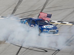 Brad Keselowski celebrates with a burnout and the American flag after winning the NASCAR Sprint Cup Aaron’s 499 at Talladega on Sunday.