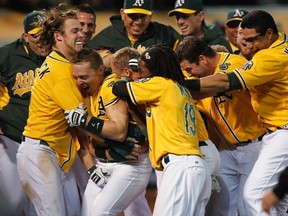 Athletics baserunner Brandon Inge (bottom left) is mobbed by teammates after hitting a walk-off grand slam against the Blue Jays at the O.co Coliseum in Oakland, Calif., May 8, 2012. (BECK DIEFENBACH/Reuters)