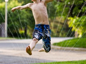 James Pluscauskas, 8, jumps through a sprinkler during a hot spring day in Ottawa. (ERROL MCGIHON/QMI AGENCY)