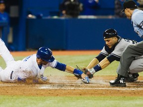 Blue Jays’ J.P. Arencibia slides around Yankees catcher Russell Martin to score a run during last night’s game at Rogers Centre. The Jays beat their AL East rivals 8-1.