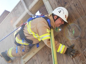 Firefighter Shawn Wilson practises using a hose to climb down from a simulated burning building, during survival training at the Wellington Street station in Sarnia on Thursday. Three provincial instructors took 10 Sarnia firefighters through the training over a five-day course. TYLER KULA/ THE OBSERVER/ QMI AGENCY