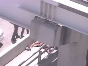 A surveillance camera on the Miami Herald building partly shows two pairs of men's legs, both naked and lying down on the roadside, are clearly visible from beneath the causeway. (Video screen grab)
