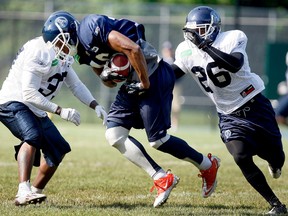 Patrick Carter does his best to try to get away from defenders Ahmad Carroll and Jordan Younger during Argos training camp at U of T Mississauga Friday. (DAVE ABEL/Toronto Sun)