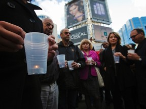 People observe a moment of silence during a candlelight vigil at Dundas Square across the street from where the shooting took place at the Toronto Eaton Centre shopping mall in Toronto, June 3, 2012. (REUTERS/Mark Blinch)