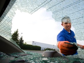 Jonathan  Bergen surveys and cleans up his back windshield. His vehicle was one of four believed damaged by falling debris from a jet which made an emergency landing at Pearson International Airport. (STAN BEHAL, Toronto Sun)