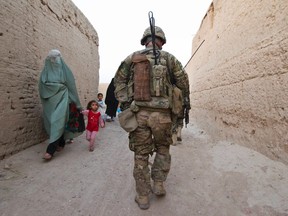 An Afghan family walks past a U.S. Army soldier of the Battle company, 1-508 Parachute Infantry battalion, 4th Brigade, 82nd Airborne Division, as he walks during a joint patrol with Afghan security forces in the town of Senjaray, Zahri district of Kandahar province, southern Afghanistan May 28, 2012.  (REUTERS/Shamil Zhumatov)