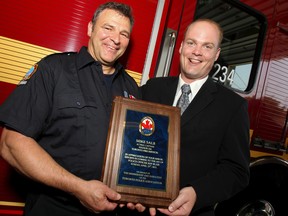 Acting Toronto Fire captain Mike Salb, left, accepts a commendation from Toronto Police and shakes hands with Toronto Police Const. Jeff Blair — inside Toronto Fire Station 234 in Scarborough Monday. (Jack Boland/Toronto Sun)