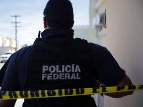 A federal police officer stands behind a police tape near a crime scene in Mexico. (REUTERS/Daniel Becerril)