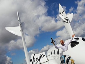 Richard Branson waves a model of the LauncherOne cargo spacecraft from a window of an actual size model of SpaceShipTwo on display, after Virgin Galactic's LauncherOne announcement and news conference, at the Farnborough Airshow 2012 in southern England July 11, 2012.  REUTERS/Luke MacGregor