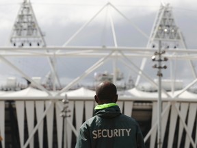 A security guard walks towards the Olympic Stadium in the London 2012 Olympic Park at Stratford in London, July 13, 2012.  Security surrounding the Olympics has made the headlines this week after Britain was forced to deploy 3,500 extra troops to fill an embarrassing last-minute shortfall in private security staff. (REUTERS/Luke MacGregor)