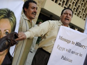 An Egyptian protester shouts slogans as he holds a shoe on a portrait of US Secretary of State Hillary Clinton outside the US embassy in Cairo on July 14, 2012 to protest against her visit to the country. (AFP PHOTO/MOHAMMED HOSSAM)