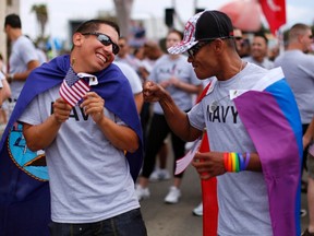 Matthew Avila (L), active duty gunners mate 2nd class U.S. Navy, receives a punch in the arm from former EN2 U.S. Navy's Ray Cordero as they prepare to march with active and non-active U.S. military personnel who are participating for the first time in San Diego's Gay Pride Parade in San Diego in this July 16, 2011 file photo. (REUTERS/Mike Blake)