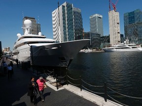 Pedestrians walk past luxury yacht Ilona, owned by former Chairman of National Car Parks Donald Gosling (L) and luxury yacht Seanna, owned by Westfield Group co-founder Frank Lowy, which are moored in Canary Wharf for the 2012 London Olympics, in London July 23, 2012. (REUTERS/Suzanne Plunkett)