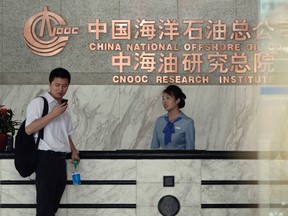 The man stands at the front desk of the headquarters of China National Offshore Oil Corp (CNOOC) in Beijing July 25, 2012. When Canada's Nexen Inc fired its CEO in January, an oil giant on the other side of the world sprang into action. Nexen had been on the wish list of Chinese state oil company CNOOC Ltd for five years. By the Chinese New Year later that month, CNOOC had hired BMO Capital Markets and Citigroup Inc as financial advisers, according to these sources. (Jason Lee/REUTERS)