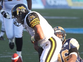 Hamilton Tiger-Cats quarterback Henry Burris loses control of the ball while being hit by Blue Bombers defensive end Alex Hall during last night’s game in Winnipeg. (Brian Donogh/QMI Agency)