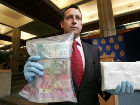 Staff Sgt. Kevin Brezinski poses with over $1 million in seized drugs and money at the downtown Police Headquarters in Edmonton, Alberta on April 28, 2011. (PERRY MAH/EDMONTON SUN FILE)
