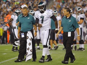 Philadelphia Eagles quarterback Michael Vick (C) reacts as he is escorted off of the field after being sacked by New England Patriots linebacker Jermaine Cunningham (not pictured) during the first quarter of their preseason NFL football game in Foxborough, Massachusetts August 20, 2012. (Reuters/JESSICA RINALDI)