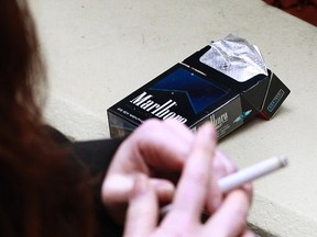 A woman smokes next to a cigarette pack in this October 12, 2011 file photo. (Reuters/DANIEL MUNOZ/Files)