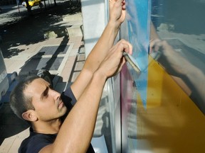 Federico Herrero installs his window murals at the Contemporary Art Gallery.  Wayne Leidenfrost/ PNG