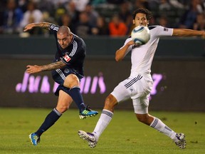 Eric Hassli of the Vancouver Whitecaps puts a shot on goal in the first half under pressure from Omar Gonzalez of the Los Angeles Galaxy during their MLS match at The Home Depot Center on September 17, 2011 in Carson, Calif. The Galaxy defeated the Whitecaps 3-0.  (Photo by Victor Decolongon/Getty Images)
