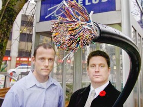 CABLE theft is hurting Telus - PICTURE of Shawn Hall (right) and Rob Cook (left) from Telus showing cut end of cable containing cooper wiring - phone booths (such as the one in picture) are also targets .. Bill Keay/Vancouver Sun photo