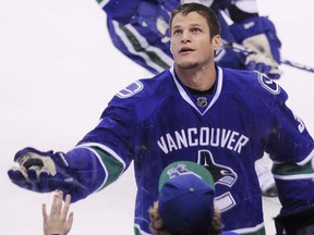 Vancouver Canucks defenceman Kevin Bieksa tosses a puck over the glass to a fan wearing a Bieksa jersey during the pre-game skate prior to the Canucks’ game against the St Louis Blues at Rogers Arena on Wednesday. (Photo by Gerry Kahrmann, PNG)