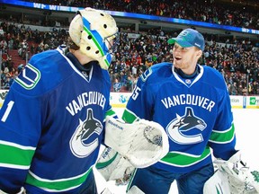 Roberto Luongo (left) and Cory Schneider in earlier times, when the roles were reversed — ie., Luongo playing and Schneider looking good in a ball cap. (Photo by Jeff Vinnick, NHLI via Getty Images)