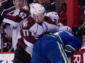 VANCOUVER, CANADA - DECEMBER 6: Keith Ballard #4 of the Vancouver Canucks is hit by Chuck Kobasew #17 of the Colorado Avalanche during the first period in NHL action on December 06, 2011 at Rogers Arena in Vancouver, British Columbia, Canada.  (Photo by Rich Lam/Getty Images)