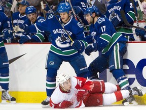 VANCOUVER, CANADA - DECEMBER 21: Kevin Bieksa # and Ryan Kesler #17 of the Vancouver Canucks team up to knock down Valtteri Filppula #51 of the Detroit Red Wings during the third period in NHL action on December 21, 2011 at Rogers Arena in Vancouver, British Columbia, Canada.  (Photo by Rich Lam/Getty Images)