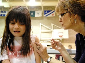 REGINA, SK.: NOVEMBER 13, 2009 -- Eight-year-old Eve Lemoine in grade 3 at Ecole Monseigneur de Laval receives her H1N1 flu shot from public health nurse Karen Baily with the Regina Qu'Appelle Health Region during school hours in Regina on Nov 13, 2009.  Eve's father, Remi is the principal but that didn't make Eve any less squeamish.
(Don Healy / Leader-Post)
(Story by Pam Cowan) (NEWS)