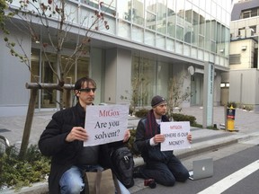 Bitcoin trader Kolin Burges, right, of London and American Aaron (only his first name was given) hold protest signs as they conduct a sit-in in front of the office tower housing Mt. Gox in Tokyo Tuesday, Feb. 25, 2014.