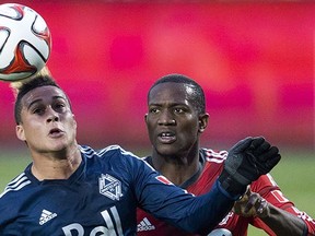 Vancouver Whitecaps striker Eric Hurtado (left) and Toronto FC defender Doneil Henry vie for the ball during Wednesday’s first-leg Amway Canadian Championship semifinal in Toronto.