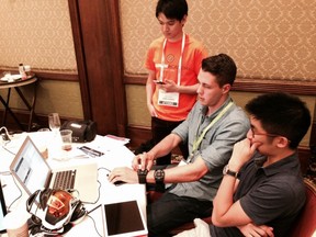 At the GROW hackathon in Whistler, Kiip CEO Brian Wong, right, helps a team that is trying to incorporate his company’s virtual rewards with an app that works with Recon goggles.