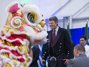 Vancouver Mayor Gregor Robertson makes a face at the Chinese Lion during a dance after being sworn in during a ceremony in Vancouver, B.C., Monday, Dec. 8, 2014. THE CANADIAN PRESS/Jonathan Hayward
