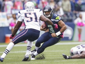 Russell Wilson of the Seattle Seahawks rushes the ball against Jerod Mayo of the New England Patriots during a game at CenturyLink Field on October 14, 2012 in Seattle, Washington. The Seahawks beat the Patriots 24-23.