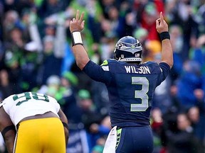 Thrill of victory, agony of defeat: Quarterback Russell Wilson of the Seattle Seahawks celebrates the game-winning overtime touchdown while Green Bay Packers lineman Letroy Guion doubles over at the end of the NFC Championship Game on Sunday in Seattle. (Ronald Martinez, Getty Images)