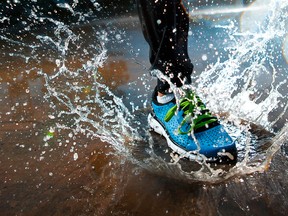 Single runner running in rain and making splash in puddle