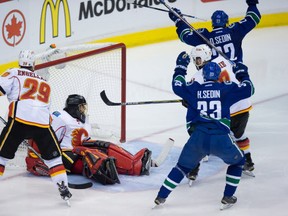Vancouver Canucks' Daniel Sedin (22), of Sweden, and Henrik Sedin (33), of Sweden, celebrate Daniel's goal against Calgary Flames' goalie Jonas Hiller, of Switzerland, as Deryk Engelland (29) and T.J. Brodie (7) watch during the third period of game 5 of an NHL Western Conference first round playoff hockey series in Vancouver, B.C., on Thursday April 23, 2015. THE CANADIAN PRESS/Darryl Dyck