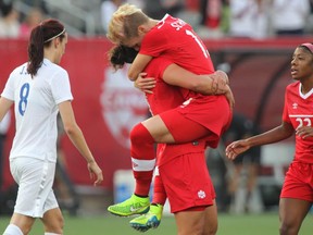 Canada's Sophie Schmidt leaps into the arms of Melissa Tancredi after scoring against England during a womens' international soccer friendly match in Hamilton, Ontario on Friday May 29, 2015. The two teams meet again Saturday, 4:30 p.m., in a World Cup quarter-final at BC Place in Vancouver.