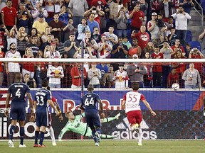 Vancouver Whitecaps goalkeeper David Ousted deflects away a penalty kick by New York Red Bulls forward Bradley Wright-Phillips (far right) during the Whitecaps’ 2-1 victory on Saturday in Harrison, N.J. (Julio Cortez, Associated Press)