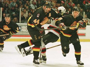 Defenceman Dave Babych (centre) does look menacing in black, laying out a New Jersey Devils player while almost also taking out teammate Mike Sillinger (right) during an early 1990s NHL game. (Getty Images files)