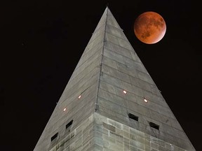 The so-called supermoon passes behind the peak of the Washington Monument during a lunar eclipse, Sunday, Sept. 27, 2015. The supermoon, or perigee moon, occurs when the full or new moon comes closest to the Earth making it appear bigger. t's the first time the events have made a twin appearance since 1982, and they won't again until 2033. (AP Photo/J. David Ake)