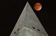 The so-called supermoon passes behind the peak of the Washington Monument during a lunar eclipse, Sunday, Sept. 27, 2015. The supermoon, or perigee moon, occurs when the full or new moon comes closest to the Earth making it appear bigger. t's the first time the events have made a twin appearance since 1982, and they won't again until 2033. (AP Photo/J. David Ake)