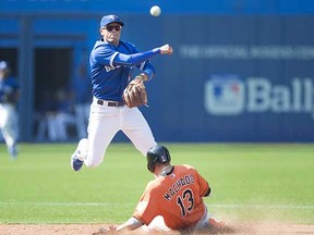 Toronto Blue Jay Ryan Goins turns a double play over Baltimore Orioles base runner Manny Machado during a Sept. 5 American League game in Toronto. (Darren Calabrese, Canadian Press)