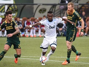Vancouver Whitecaps midfielder Gershon Koffie tries to get past Portland Timbers defenders Liam Ridgewell (left) and Nat Borchers (right) during the first half of their MLS western conference semifinal match in Portland, Ore., on Sunday. (Steve Dykes, Associated Press)