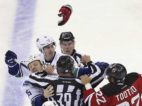 New Jersey Devils right-winger Jordin Tootoo fights with Vancouver Canucks wingers Derek Dorsett (left) and Alex Burrows during the second period of their NHL game on Sunday in Newark, N.J. (Mel Evans, Associated Press)