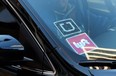 A driver displaying Lyft and Uber stickers on his front windshield drops off a passenger in downtown Los Angeles, Calif. Passengers arriving at Los Angeles International Airport will be allowed to leave in an UberX car starting Thursday, Jan. 21.