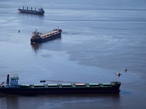 Spill response boats work to contain bunker fuel leaking from the bulk carrier cargo ship Marathassa, second from top, anchored on Burrard Inlet in Vancouver, B.C., on Thursday April 9, 2015. THE CANADIAN PRESS/Darryl Dyck