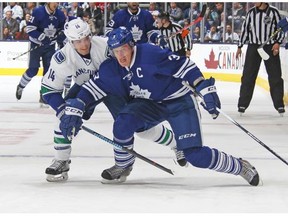 Alex Burrows #14 of the Vancouver Canucks takes a hooking penalty against Dion Phaneuf #3 of the Toronto Maple Leafs during an NHL game at the Air Canada Centre on November 14, 2015 in Toronto, Ontario, Canada.
